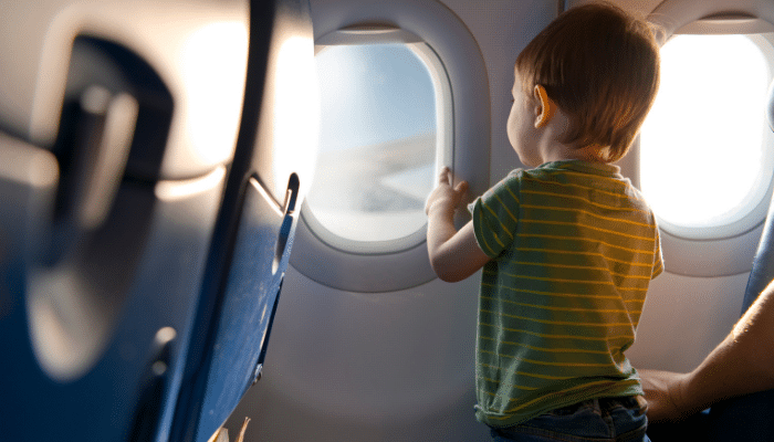 Enfant regarde hublot avion, voyage en famille