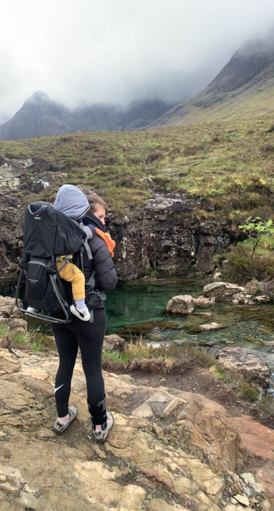 Maman avec bébé en porte-bébé pendant une randonnée aux Fairy Pools sur l’île de Skye